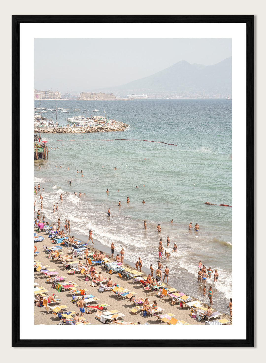 Beach scene with people and umbrellas near a body of water with mountains in the background. Summer Beach Mountain View by Henrike Schenk is a Mediterranean beach photography print featuring coastal views, mountains, ocean scenery, and summer travel.