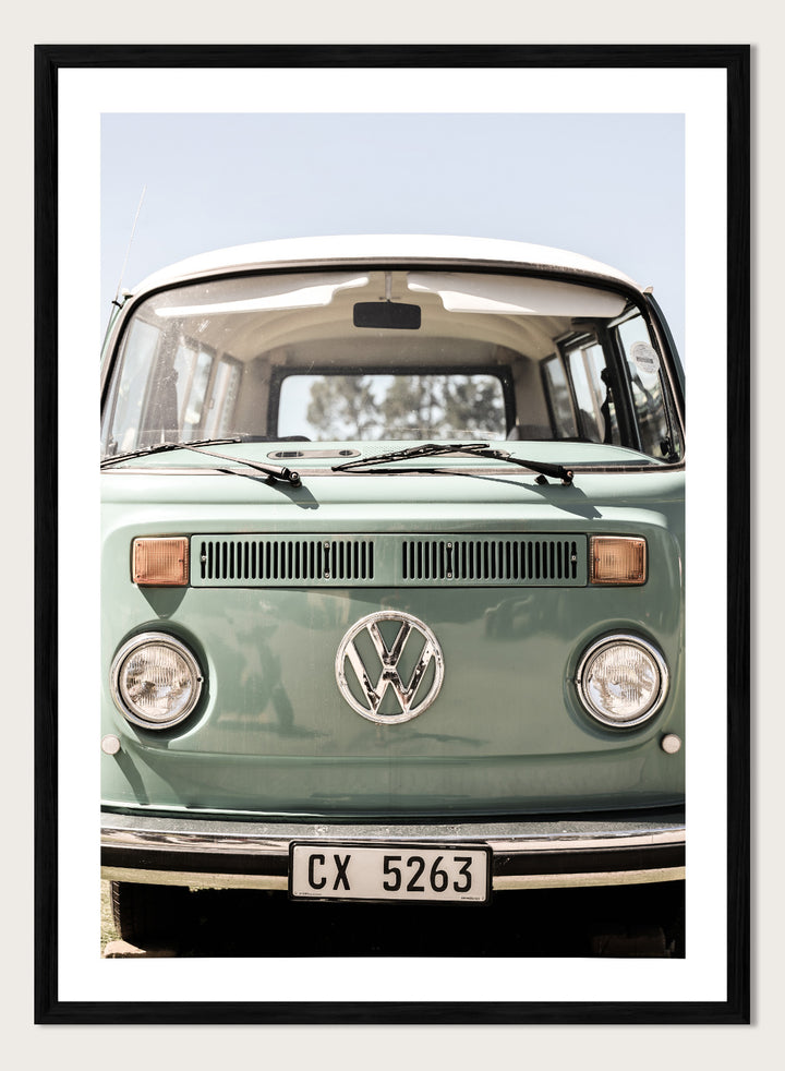 Front view of a vintage green Volkswagen van with clear sky background. Classic Design In Soft Green Tones by Shot by Clint car art print featuring a vintage Volkswagen camper van in soft sage green and warm sunlight.