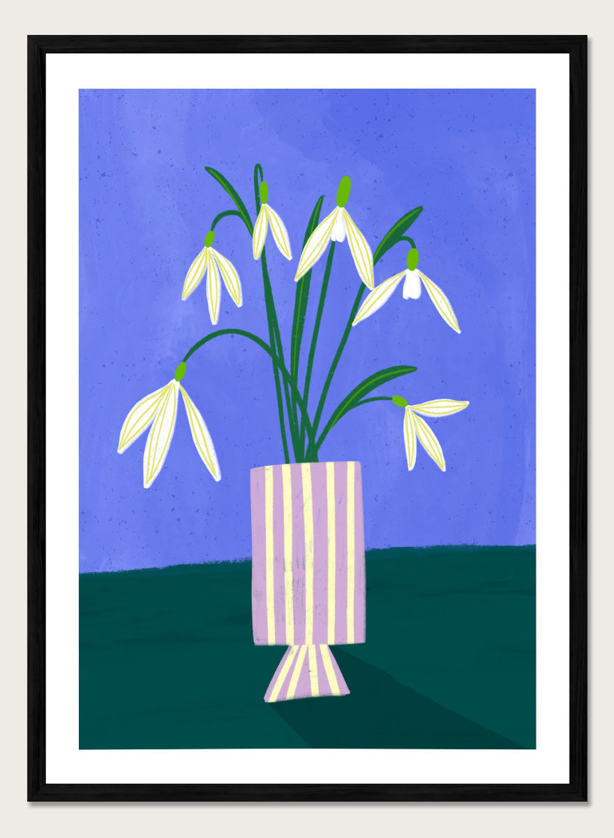 A framed art print featuring a stylized illustration of white snowdrops with green stems in a lavender and cream striped vase, set against a blue and dark green background. Snowdrops in Striped Vase by Bea Müller fine art print featuring white snowdrops, a lilac striped vase, and a deep blue background.