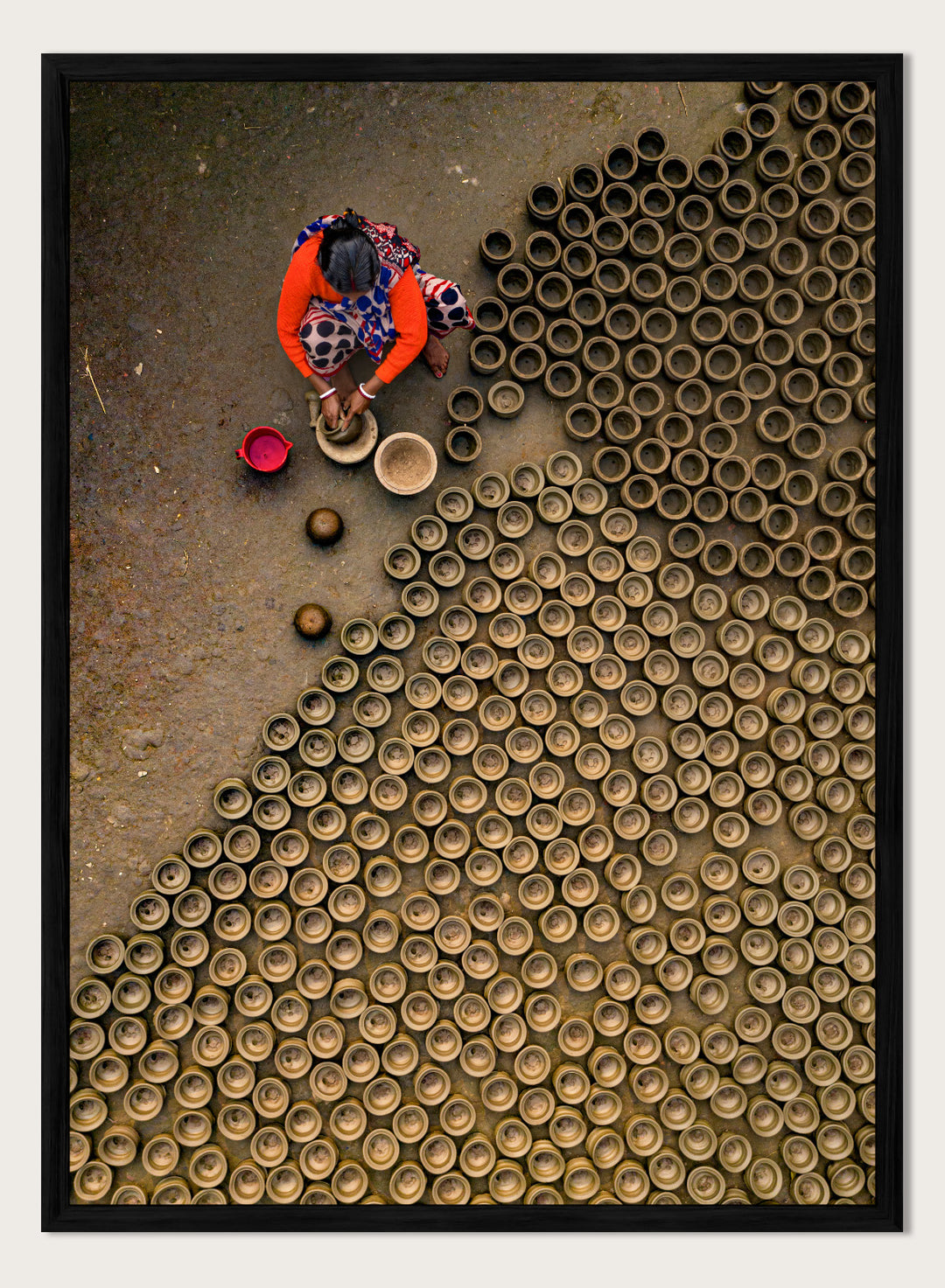 Person working with clay pots on a textured surface. Pot Making by Azim Khan Ronnie aerial photography print showing clay pots drying in Bangladesh village, traditional craft wall art poster
