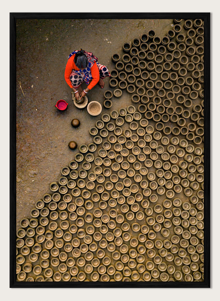 Person working with clay pots on a textured surface. Pot Making by Azim Khan Ronnie aerial photography print showing clay pots drying in Bangladesh village, traditional craft wall art poster