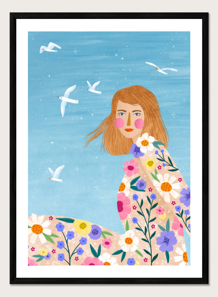 A framed art print featuring a stylized illustration of a young woman with long light brown hair, surrounded by colorful flowers and white birds against a light blue sky. ree Spirit Floral Dreams by Bea Müller floral woman art print featuring a flowing flower-covered summer dress, white birds, and a bright blue sky.
