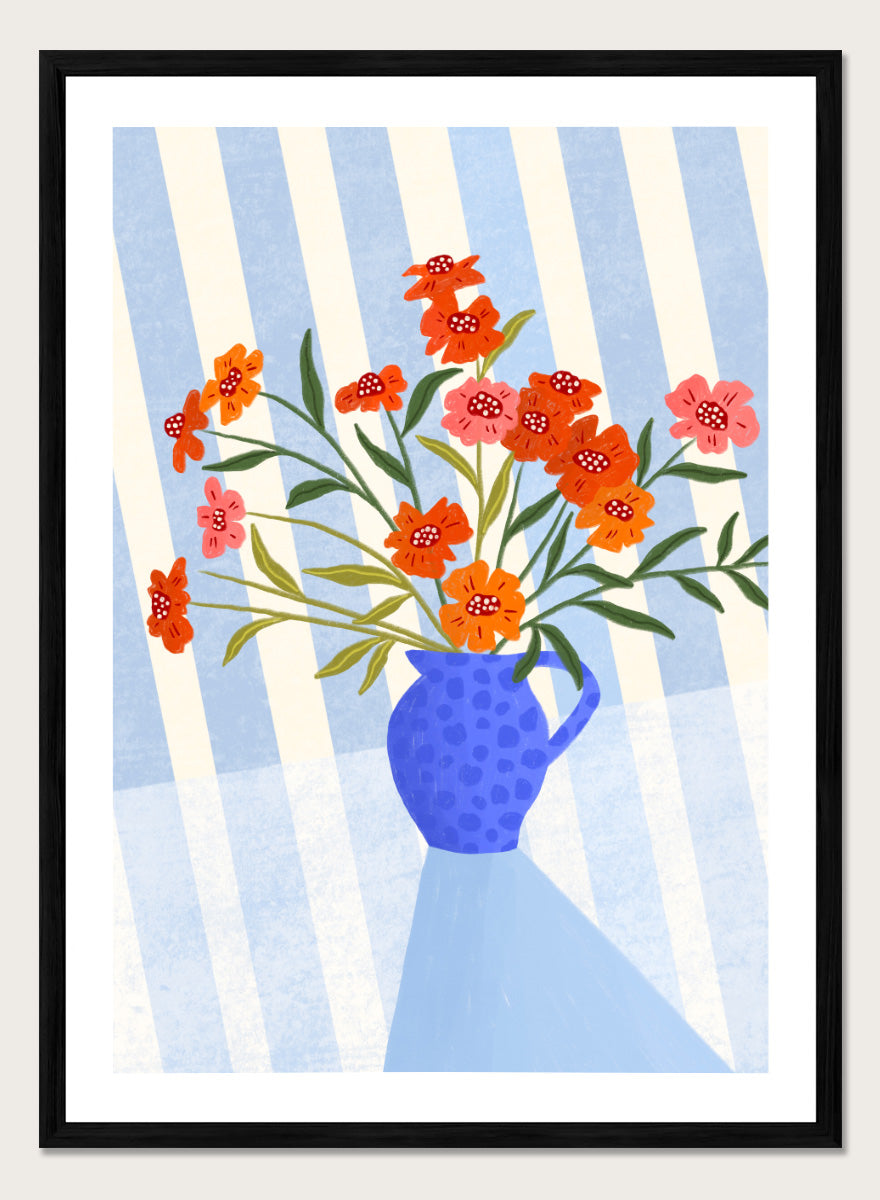 A framed art print featuring a stylized illustration of a blue patterned pitcher vase filled with orange, red, and pink flowers against a blue and white striped background. Cheerful Floral Pitcher by Bea Müller floral still life art print featuring orange and pink flowers in a bright blue jug with striped blue decor.