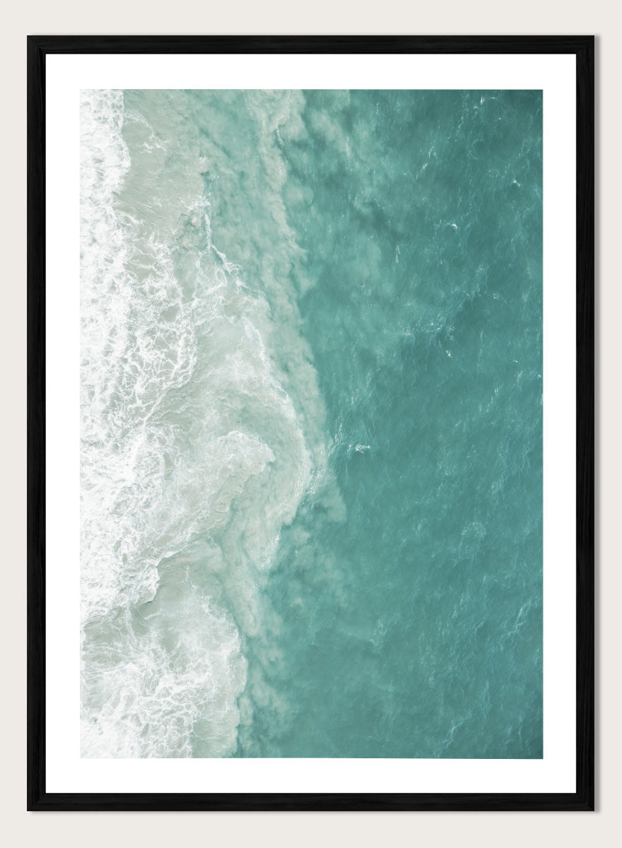 A framed aerial photograph of ocean waves, showing white foam breaking into turquoise and teal water. Ocean’s Edge by Shot by Clint aerial ocean photography print featuring turquoise water, white surf, and layered coastal movement.